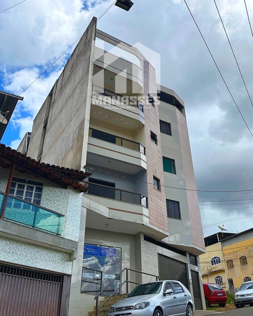 Fachada de um prédio residencial de cinco andares com varanda e garagem, localizado em uma rua urbana com céu parcialmente nublado.