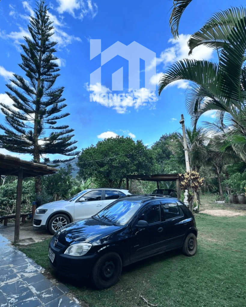 Área externa com dois carros estacionados ao lado de varanda coberta, cercada por árvores e vegetação em chácara no Córrego Guarani, Reduto MG.