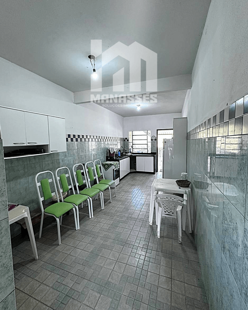 Cozinha ampla com paredes revestidas de azulejo verde e cadeiras alinhadas – Manassés Soluções Imobiliárias