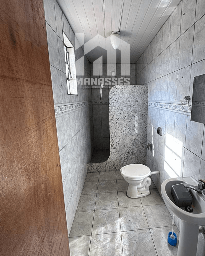Banheiro de suíte simples revestido de azulejos claros com box separado – Manassés Soluções Imobiliárias.