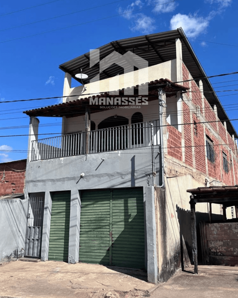 Casa de dois andares com ponto comercial à venda no distrito de São Caetano, Caputira/MG, fachada lateral em tijolo aparente e portões verdes.