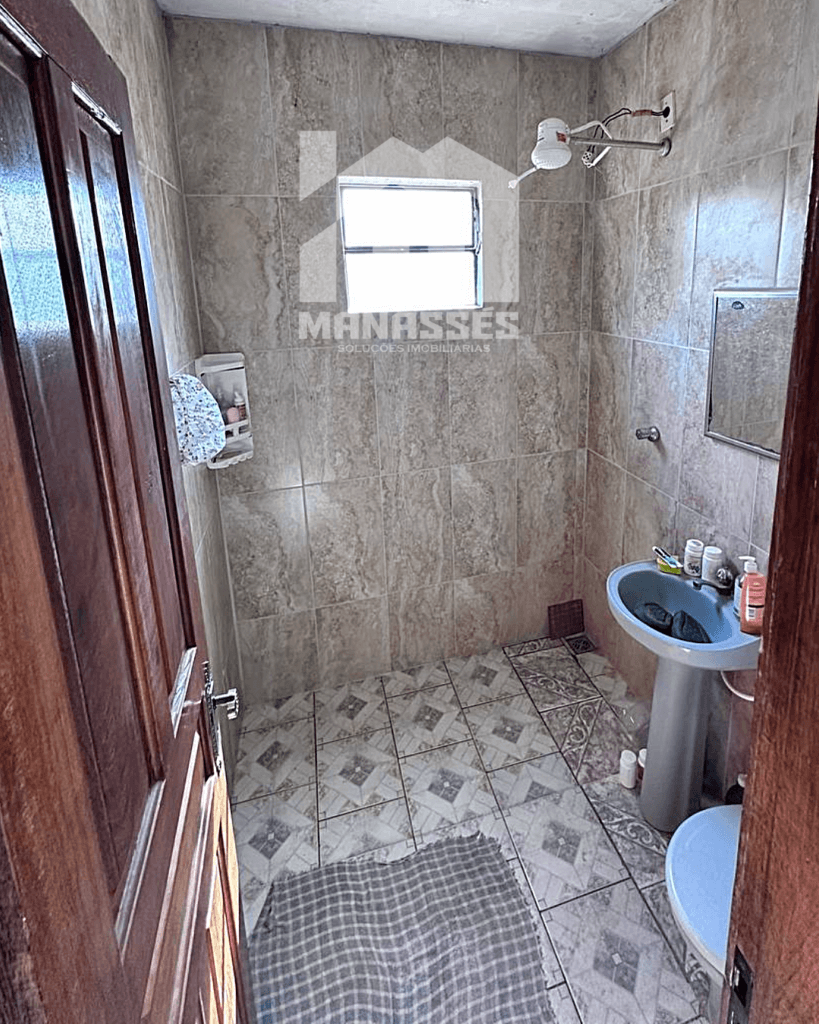 Banheiro simples com revestimento cerâmico e pia azul – Manassés Soluções Imobiliárias.