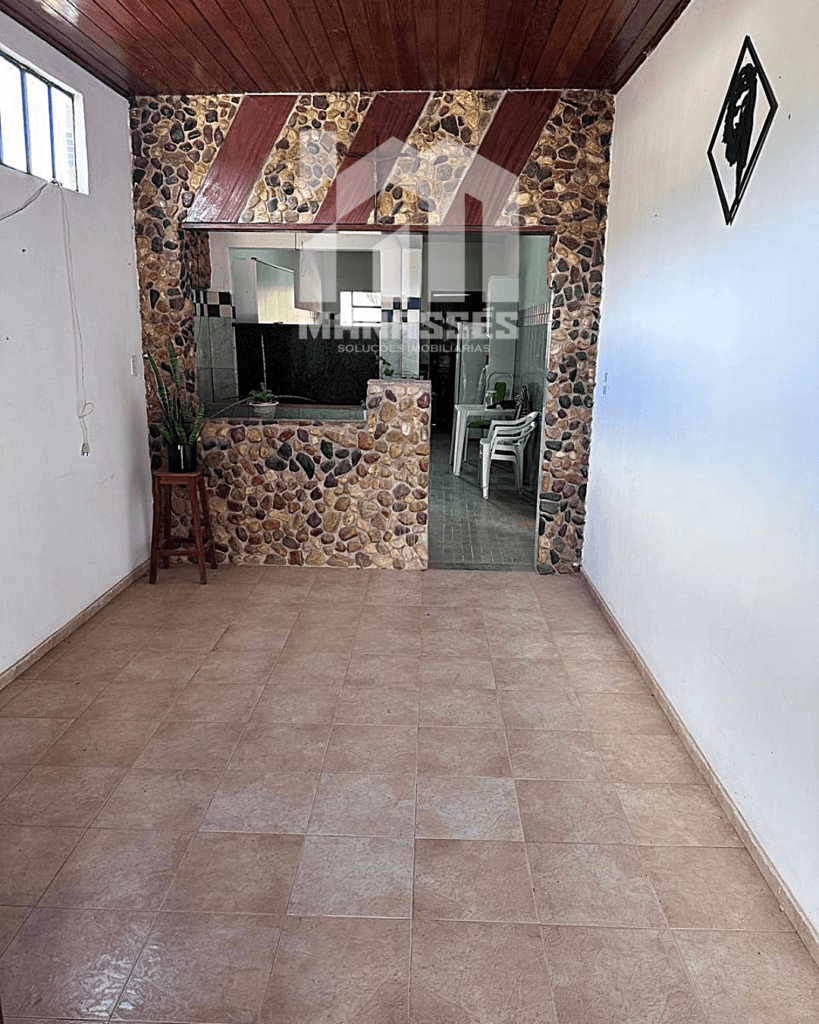 Área interna de casa à venda em São Caetano-MG, com piso cerâmico, balcão revestido em pedras decorativas e acesso para cozinha, disponível na Manassés Soluções Imobiliárias.