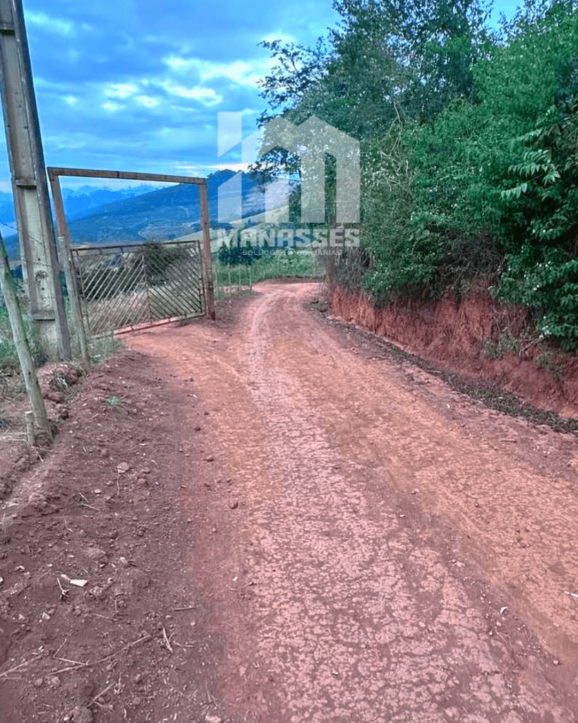 Estrada de terra com portão de entrada para terreno à venda no Córrego Sinceridade, em Manhuaçu MG, cercada por vegetação e com vista para montanhas ao fundo.