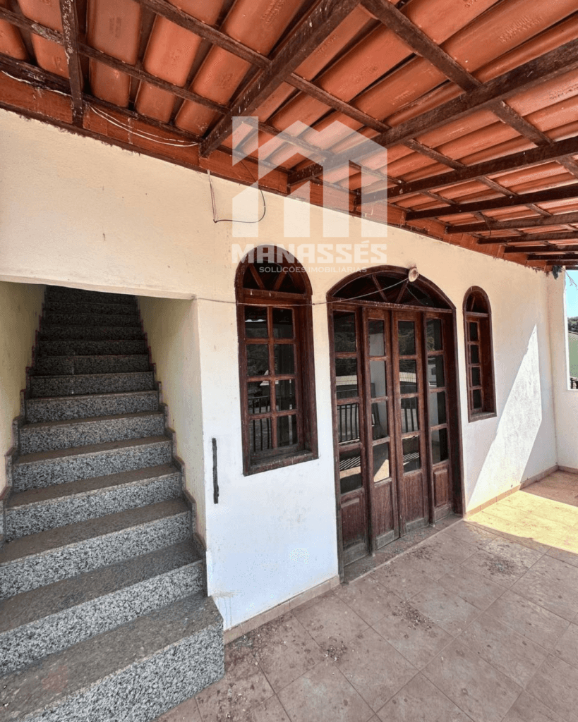 Varanda coberta com escada de granito e portas de madeira envidraçadas, em imóvel à venda pela Manassés Soluções Imobiliárias.
