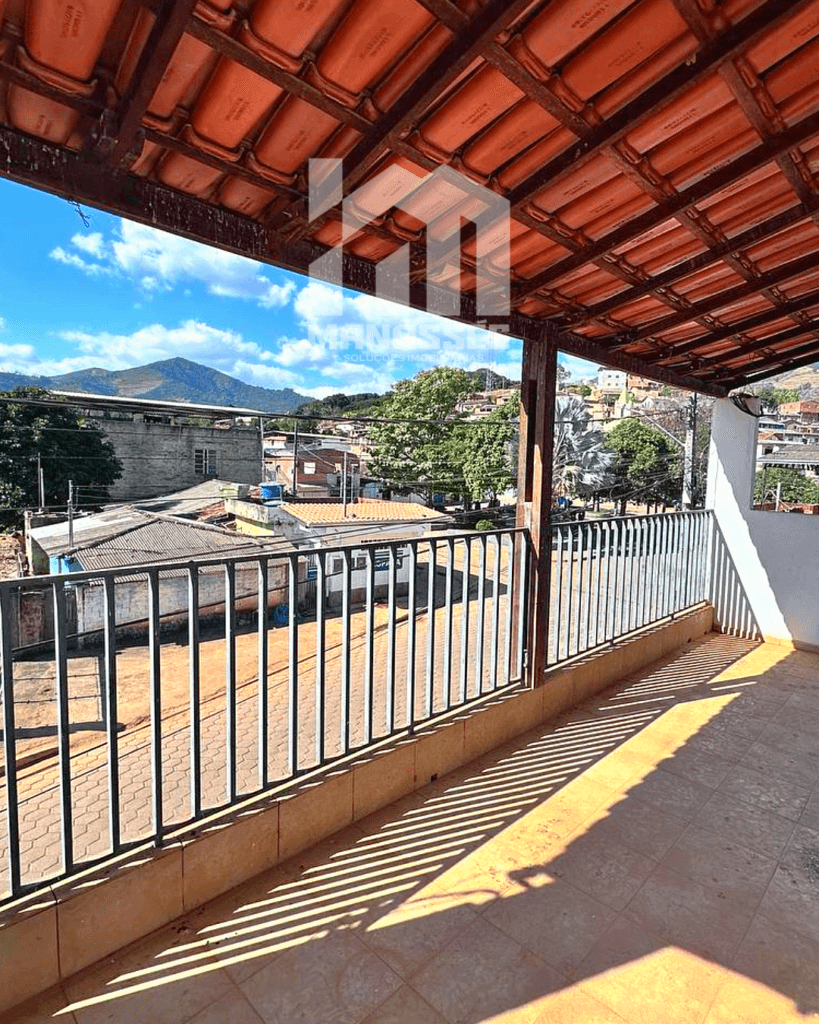 Varanda coberta com vista panorâmica para a cidade e montanhas, em imóvel à venda pela Manassés Soluções Imobiliárias.