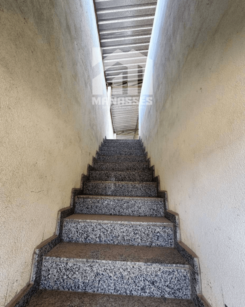 Escada interna revestida de granito, com acesso ao pavimento superior, em imóvel da Manassés Soluções Imobiliárias.
