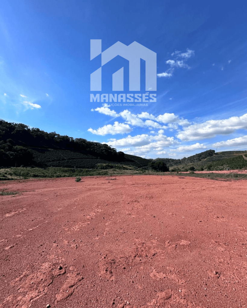 Terreno amplo e totalmente plano, com solo avermelhado e vista para colinas verdes, localizado às margens da BR-262 em Manhuaçu, Minas Gerais — ideal para investimento imobiliário, construção comercial ou residencial.