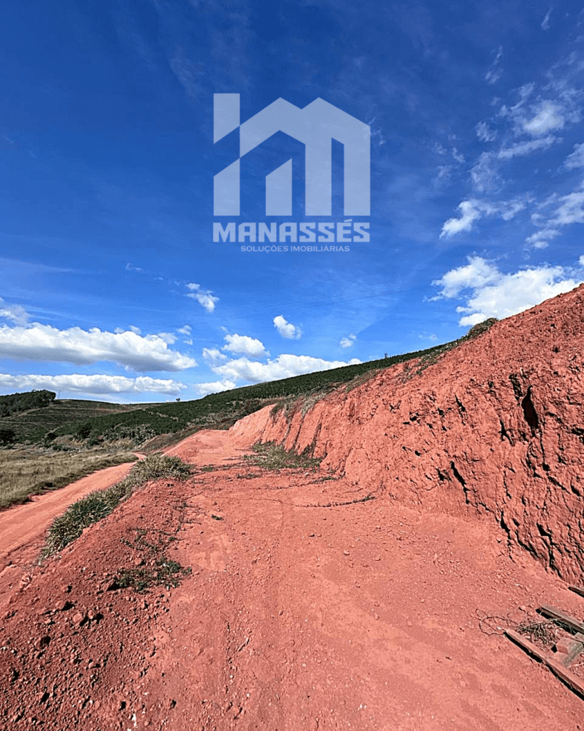 Terreno amplo com solo avermelhado e talude natural, localizado às margens da BR-262 em Manhuaçu/MG, ideal para construção ou investimento imobiliário.