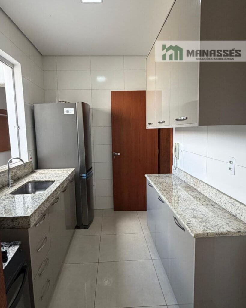 Cozinha planejada com armários embutidos, bancada em granito e acabamento moderno em imóvel residencial à venda em Manhuaçu.
