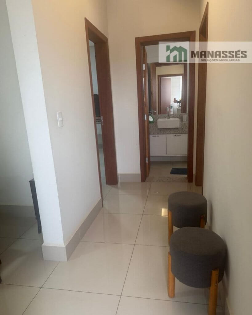 Corredor interno com piso em porcelanato, portas em madeira e acesso à suíte em imóvel residencial à venda em Manhuaçu.