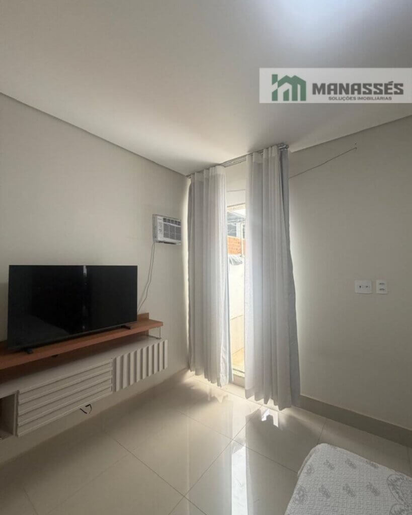 Quarto residencial com ar-condicionado, painel para TV, piso em porcelanato e iluminação natural em imóvel à venda em Manhuaçu.