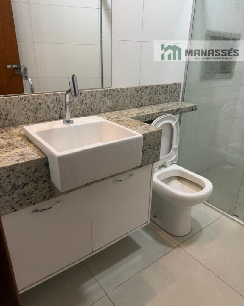 Banheiro de suíte com bancada em granito, cuba de apoio, armário planejado e box de vidro em imóvel residencial disponível para venda em Manhuaçu.