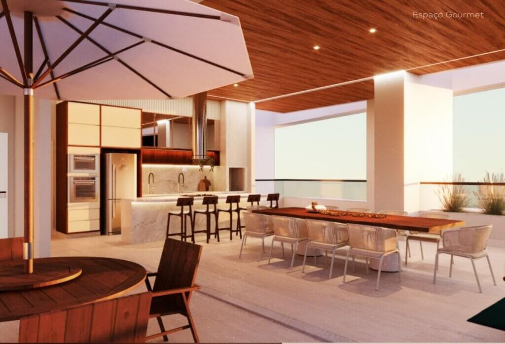 Perspectiva do Espaço Gourmet integrado ao ar livre, exibindo uma bancada com banquetas, uma longa mesa de jantar em madeira, cozinha planejada ao fundo e teto revestido em madeira.