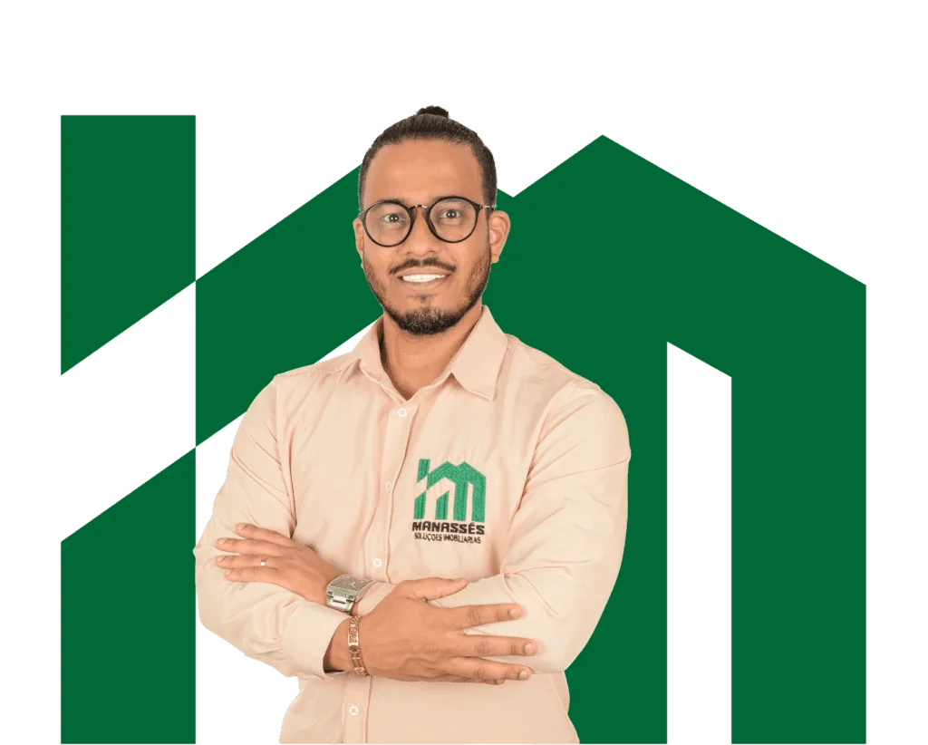 Consultor imobiliário sorridente de braços cruzados usando camisa bege com logo verde da Manassés Soluções Imobiliárias, diante de fundo preto com símbolo geométrico verde.
